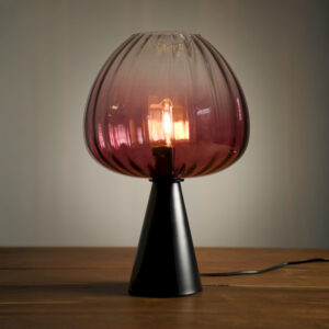 Lampe à poser design avec abat-jour en verre fumé rose et base noire. Un luminaire élégant diffusant une lumière chaleureuse et décorative.