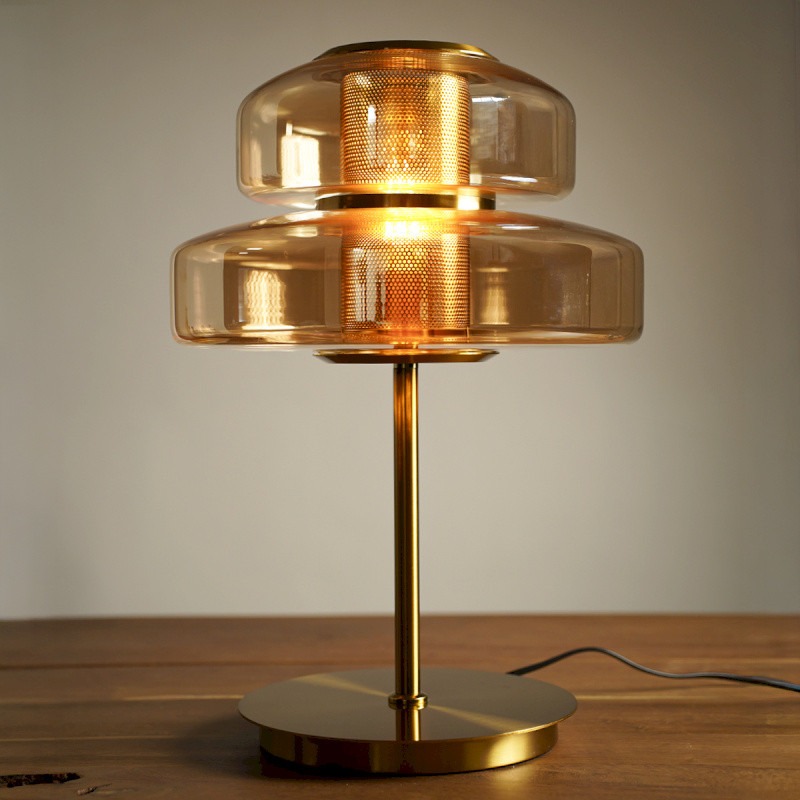 Lampe à poser design en verre ambré et métal doré avec diffuseur central perforé. Un luminaire élégant et chaleureux pour salon ou chambre.