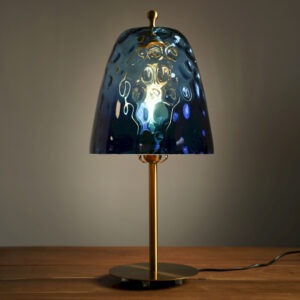 Lampe à poser design avec abat-jour en verre bleu texturé et base en métal doré. Un luminaire élégant diffusant une lumière douce et chaleureuse.