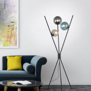 Lampadaire trepied en verre colore allume a cote d'un canape bleu dans un salon.