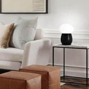 Lampe champignon noire et opaline allumee sur un meuble d'appoint pres d'un canape a Royan.