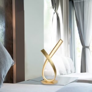 lampe-table-led-doree-ambiance-magasin-royan Lampe a poser LED doree allumee sur une table de chevet dans une chambre pres de Royan.