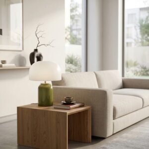 Lampe champignon en verre vert allumee sur un buffet en bois.
