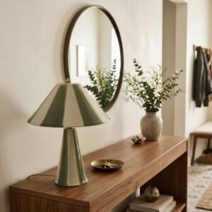 Lampe en ceramique a rayures vertes allumee sur une console en bois dans une entree pres de Royan.