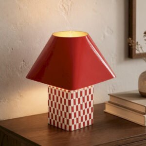 Lampe en metal rouge allumee sur un meuble en bois fonce pres de Royan.