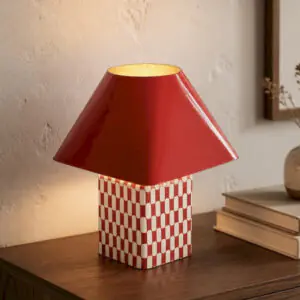 Lampe en metal rouge allumee sur un meuble en bois fonce pres de Royan.