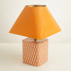 Lampe a poser geometrique en ceramique orange avec socle cubique a motif et abat-jour pyramidal.