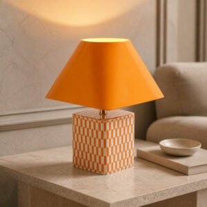 Lampe en ceramique orange allumee sur une table d'appoint en travertin pres de Royan.