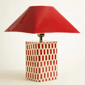 Grande lampe a poser rectangulaire en metal rouge avec socle a motif et chapeau pyramidal.