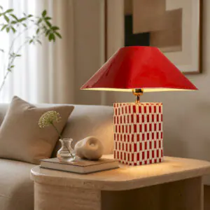 Grande lampe en metal rouge allumee sur une table en travertin dans un salon pres de Royan.
