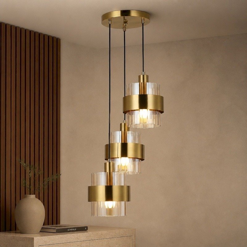 Suspension triple en laiton dore et acrylique allumee au-dessus d'un meuble en bois pres de Royan.